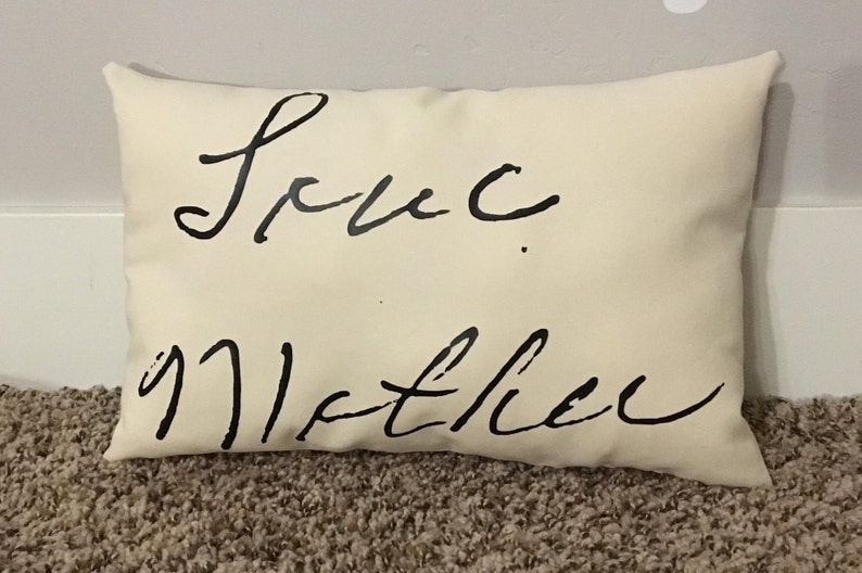 May include: A white pillow with black cursive writing that says "Love you Mother".