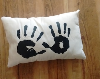 May include: White pillow with two black handprints on it.