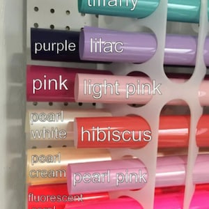 May include: A close-up of a variety of colored vinyl rolls, including tiffany, purple, lilac, pink, light pink, pearl white, hibiscus, pearl cream, pearl pink, fluorescent coral, and fluorescent pink.