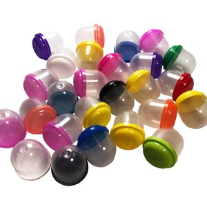 Może przedstawiać: Zbiór kolorowych plastikowych kapsułek z przezroczystymi pokrywkami. Kapsułki są w różnych kolorach, w tym czerwony, niebieski, zielony, żółty, różowy, fioletowy i czarny.