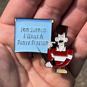 May include: A blue enamel pin with a cartoon character holding a sign that says "For Supper I Want A Party Platter".