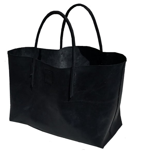 Puede incluir: Un bolso tote de cuero negro con dos asas. El bolso está vacío y tiene un aspecto ligeramente desgastado.