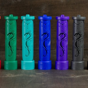 Puede incluir: Ocho contenedores cilíndricos con un diseño de dragón, cada uno en un color diferente: rojo, verde, verde azulado, azul, morado, gris y negro.