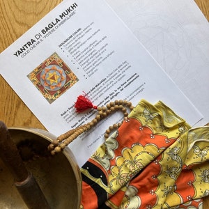 Può includere: Un Yantra di Bagla Mukhi, una divinità indu, con una descrizione dettagliata dei colori e dei simboli utilizzati nel Yantra. Il testo include la frase "Colei che ha il "potere di imbrigliare"" che si traduce come "Lei che ha il potere di legare".