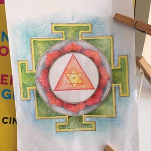 May include: A hand-drawn mandala with a green square frame, a red and orange triangle in the center, and a circle of red petals around the triangle.