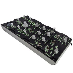 Puede incluir: Un panel de control negro con numerosos interruptores, perillas y diales, etiquetados con texto blanco. El panel tiene un marco gris y probablemente se utiliza en una aeronave o vehículo similar. Se indican varios ajustes, incluyendo "OFF", "ON" y "TEST".