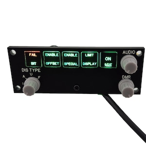 Puede incluir: Un panel de control negro con varios botones y perillas. Los botones están etiquetados como "Fail", "Enable Offset", "Enable Special", "Limit Display" y "On Alt-57 Power". Las perillas están etiquetadas como "Audio" y "DMR".