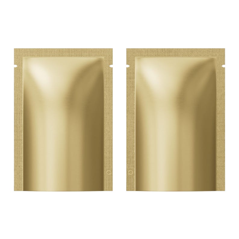 May include: Two gold-coloured, foil-like pouches with a textured, light brown border. Each pouch has a small notch at the top and a circular marking near the bottom. The pouches are likely for single-use products.