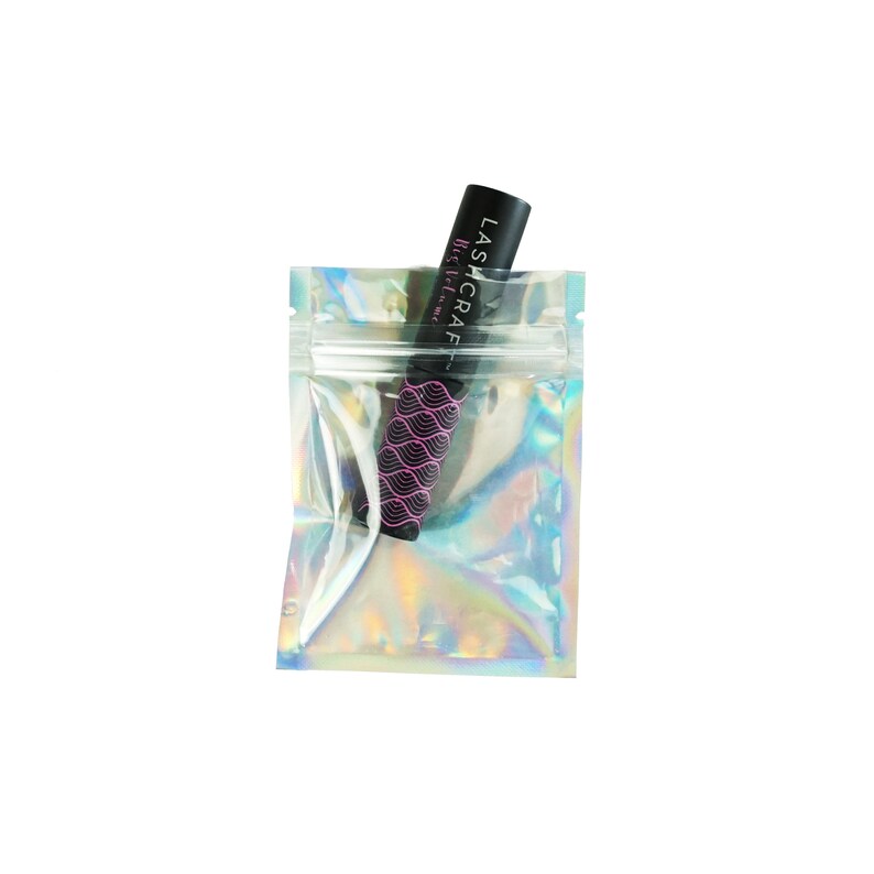 May include: A clear iridescent zippered pouch with a black mascara tube inside. The mascara tube has a pink and black design with the text "LASHCRAFT" and "Mascara" printed on it.