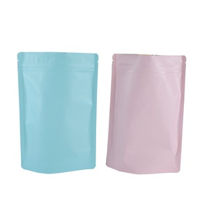 Op de afbeelding: Twee staande zakken, één lichtblauw en één roze, met een ritssluiting.