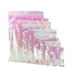 May include: A set of seven iridescent pink zippered pouches in various sizes. The pouches are made of a clear plastic material with a holographic finish.