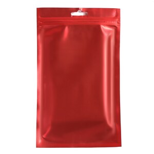 Pu&ograve; includere: Una busta di plastica rossa con cerniera e un foro per l'appeso nella parte superiore.