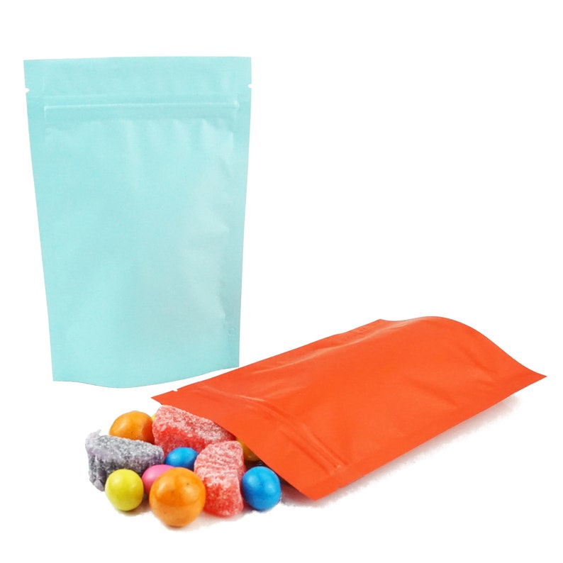 May include: Two stand-up pouches, one light blue and one orange, with colorful candy spilling out of the orange pouch.