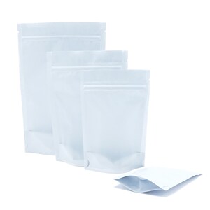 May include: Four white stand-up pouches with zipper closures. The pouches are arranged in a row, with the largest pouch at the back and the smallest pouch at the front. The pouches are made of a shiny, metallic material.