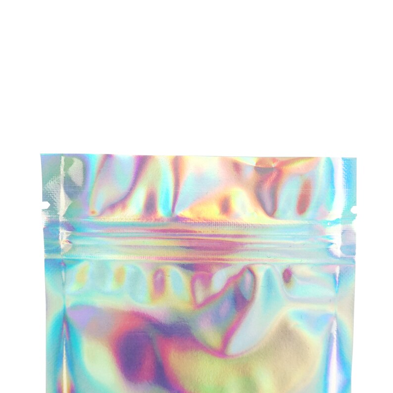 May include: A holographic iridescent silver pouch with a zipper closure. The pouch is made of a shiny, reflective material.