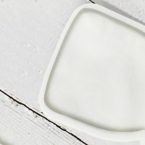 May include: A white, irregularly shaped, ceramic tray with a smooth, glossy finish.
