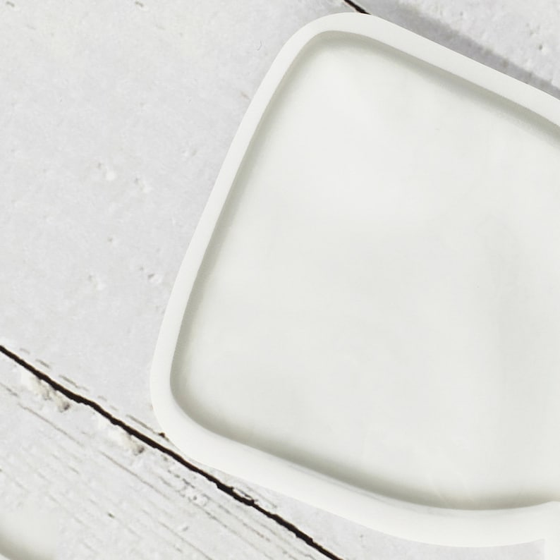 May include: A white, irregularly shaped, ceramic tray with a smooth, glossy finish.