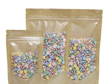 May include: Three brown paper pouches with clear front panels, each filled with colorful candy. The pouches have a zipper closure and are standing upright on a white background.