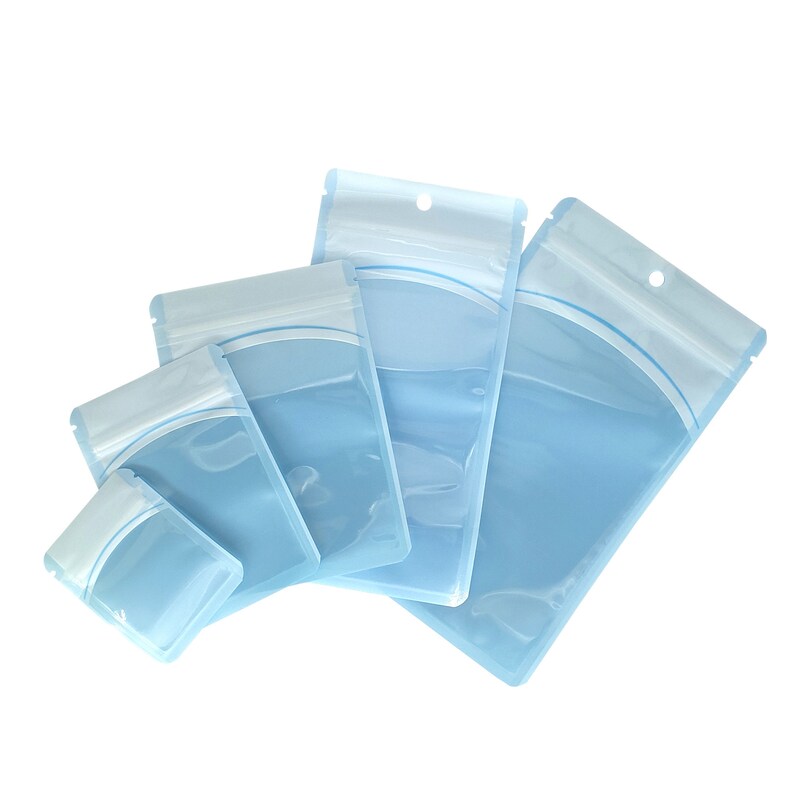 Op de afbeelding: Vier transparante plastic ritszakjes in verschillende maten, allemaal met een lichtblauwe tint en een witte rits.