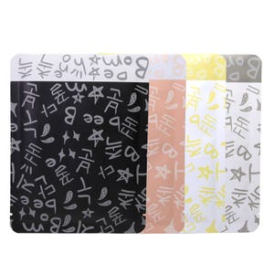 May include: Four pouches with a black, pink, yellow, and white background. Each pouch has a repeating pattern of stars, squiggles, and Korean characters in gray. The text "Bom" is visible on the top of the black pouch.