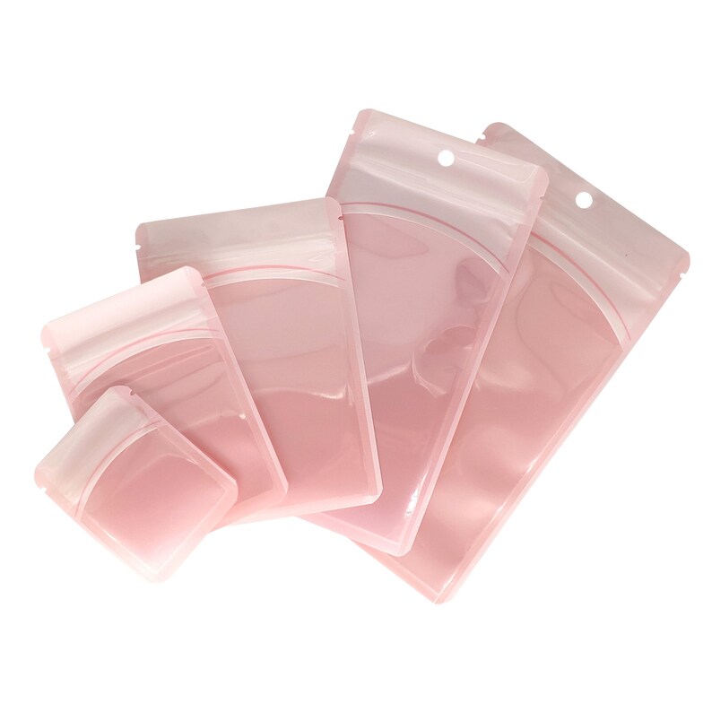 Op de afbeelding: Vier roze plastic hersluitbare zakken met een ritssluiting. De zakken zijn van verschillende grootte en zijn op elkaar gestapeld.