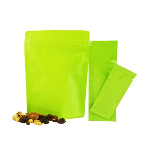 May include: Three green stand-up pouches with a zipper closure. The pouches are made of a shiny, metallic material. The largest pouch is empty, while the two smaller pouches are filled with a variety of nuts and dried fruit.
