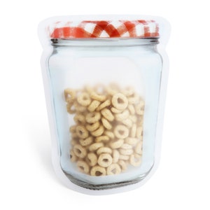 Könnte beinhalten: Eine transparente wiederverwendbare Lebensmittelverpackung aus Kunststoff in Form eines Glasbehälters mit einem rot-weiß karierten Deckel. Der Beutel ist mit Müsli gefüllt.