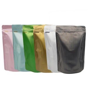 Pode incluir: Seis bolsas de pé com fecho de correr. As bolsas são feitas de um material metálico e têm um padrão listrado. As bolsas são nas seguintes cores: rosa, azul claro, verde, dourado, prateado e preto.