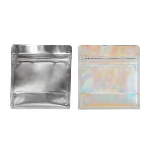 May include: Two stand-up pouches with zipper closures. The pouch on the left is silver, and the pouch on the right is iridescent.