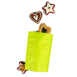 May include: A bright green stand-up pouch with a zipper closure. The pouch is empty, but there are three gingerbread cookies in the shape of a star and two hearts scattered around it.