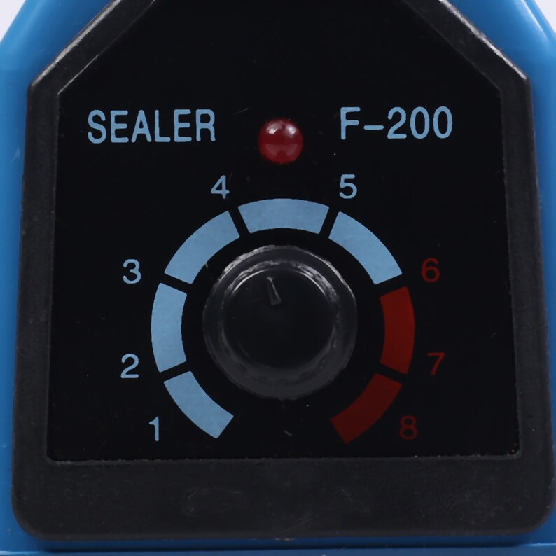 May include: A black and red control panel with a dial labeled 1 through 8. The dial is set to 5. The panel also has a red light on and the text "SEALER F-200".