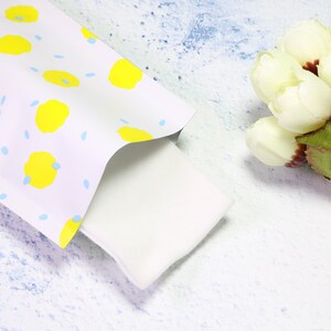 May include: A white envelope with a yellow and blue polka dot pattern. The envelope is folded over and the inside is white.