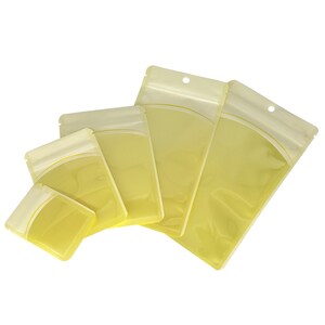 Op de afbeelding: Set van vijf doorzichtige plastic ritszakjes met een gele tint. De zakjes zijn in een waaier vorm gerangschikt, met het grootste zakje bovenaan en het kleinste zakje onderaan.
