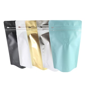 May include: A selection of stand-up pouches in diverse colours: black, white, gold, silver, and light blue. Each pouch has a zip closure and a small vent hole. The text "PULL TAB TO OPEN" is printed on the top of each pouch.