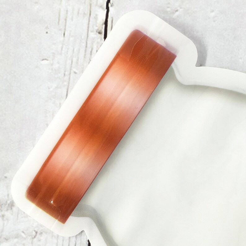 May include: A white silicone jar lid with a copper colored silicone band around the top.
