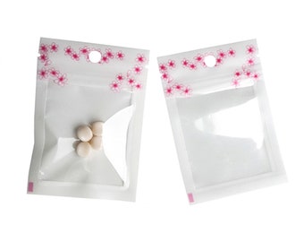 C250: witte/roze plastic reisopbergtas met mooie bloemenontwerp en doorzichtige voorkant beauty-/huidverzorgingscrèmes, scrubs en lotions (100 zakjes/pak)