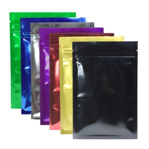 May include: A set of seven metallic zippered pouches in various colors, including green, blue, purple, red, yellow, and black. The pouches are made of a shiny, reflective material and have a zipper closure.