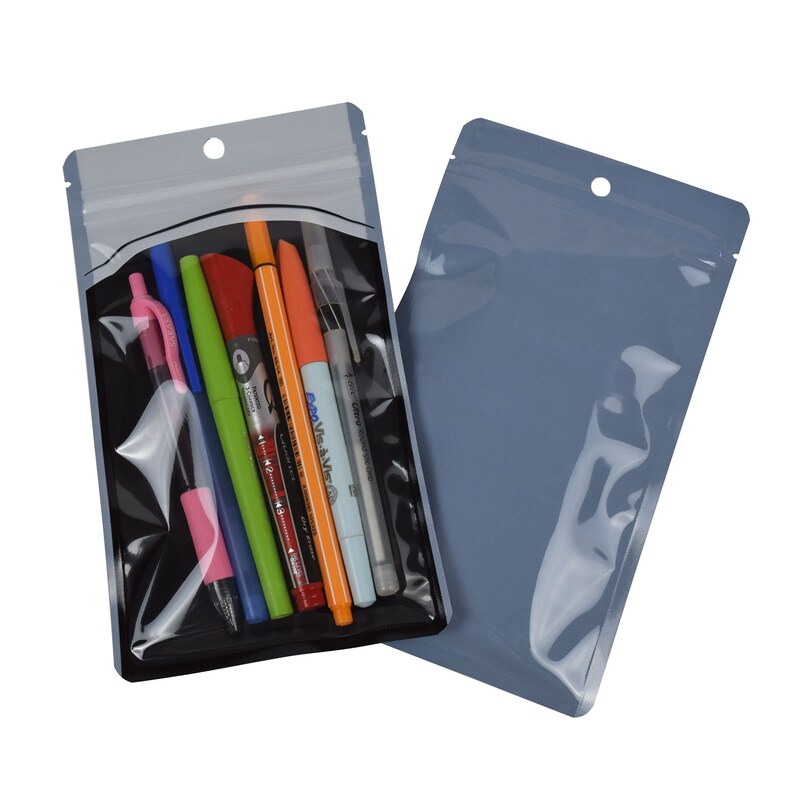 Op de afbeelding: Een set van twee doorzichtige, hersluitbare plastic zakken met een ophanggat. E&eacute;n zak is grijs en de andere is doorzichtig met een zwarte achterkant. De doorzichtige zak bevat een verscheidenheid aan pennen en stiften.