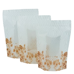 Puede incluir: Tres bolsas blancas de pie con una ventana transparente y un diseño floral marrón en la parte inferior. Las bolsas tienen una cierre de cremallera.