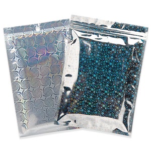 May include: Two holographic zip-top bags. One bag features a silver swirl pattern, while the other has a blue and silver starburst design. Both bags have a clear top section and a small hole near the top for hanging.