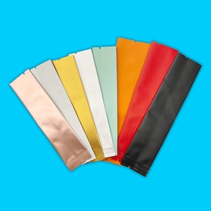 May include: A variety of colors of stand-up pouches with a flat bottom and a zipper closure. The pouches are made of a shiny, metallic material. The colors include gold, silver, black, red, orange, and light blue.