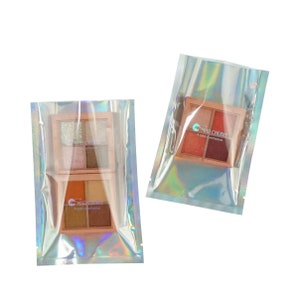 May include: Two iridescent holographic plastic bags with a 4-color eyeshadow palette inside each. The eyeshadow palettes are labeled "MAD CHERRY 4 color eyeshadow".