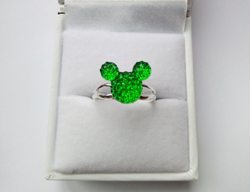 K&ouml;nnte beinhalten: Ein silberner Ring mit einem gr&uuml;nen, glitzernden Mickey Mouse Kopf-Design.
