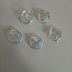 May include: Five silver hair clips with a sparkly Mickey Mouse design. Each clip is a double spiral.