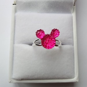 K&ouml;nnte beinhalten: Ein silberner Ring mit einem pinkfarbenen, glitzernden Mickey-Maus-Kopf-Design.