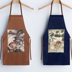 May include: Two brown and navy blue aprons with adjustable straps. Each apron features a different Japanese-style illustration of a tiger. The brown apron has a tiger with a dragon in the background. The navy blue apron has a tiger with a forest scene in the background.