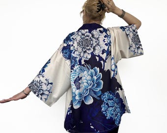 May include: A white kimono with a blue floral pattern. The kimono has a wide, flowing silhouette and is perfect for layering over other clothing.