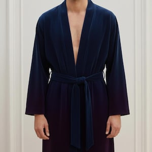 May include: A navy blue velvet robe with a matching belt tied at the waist. The robe has long sleeves and a shawl collar. The fabric appears to have a subtle color gradient, transitioning from navy to a darker shade.