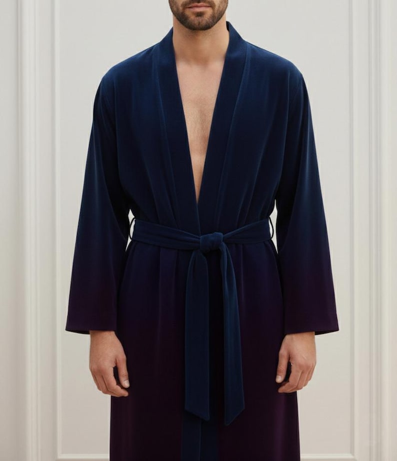 May include: A navy blue velvet robe with a matching belt tied at the waist. The robe has long sleeves and a shawl collar. The fabric appears to have a subtle color gradient, transitioning from navy to a darker shade.