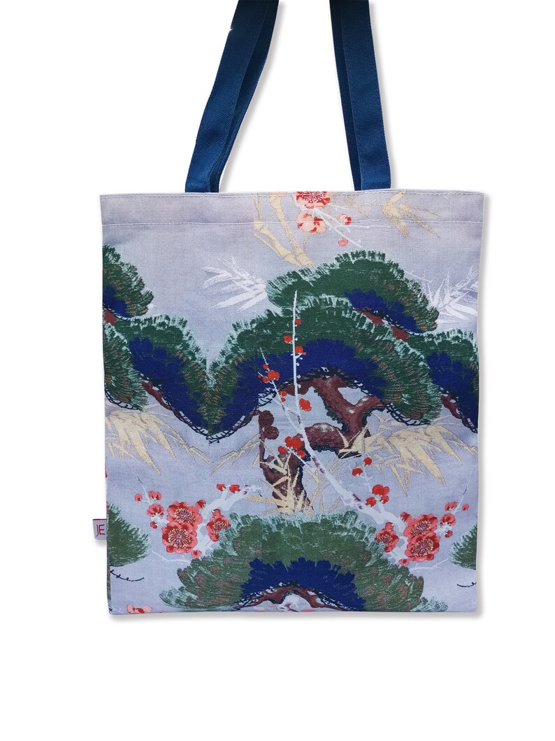 May include: A light blue tote bag with navy blue handles. The bag features a floral print with green, blue, and red flowers and leaves.
